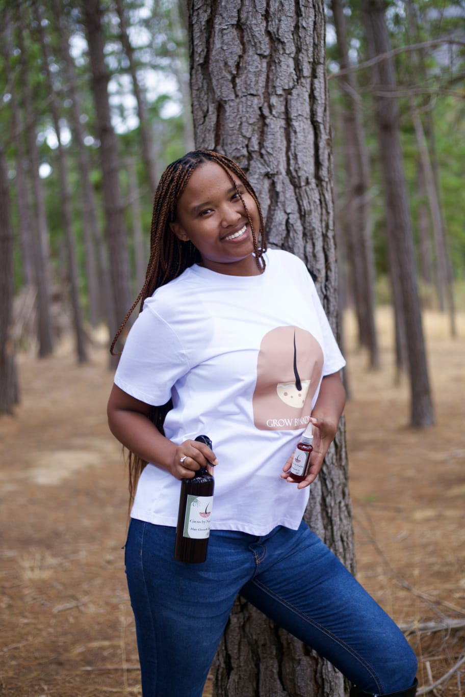 Nadine, founder and owner of Grow by Nadine, holding her hair-care products